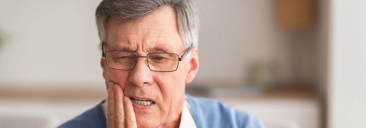 older man holding his jaw in pain