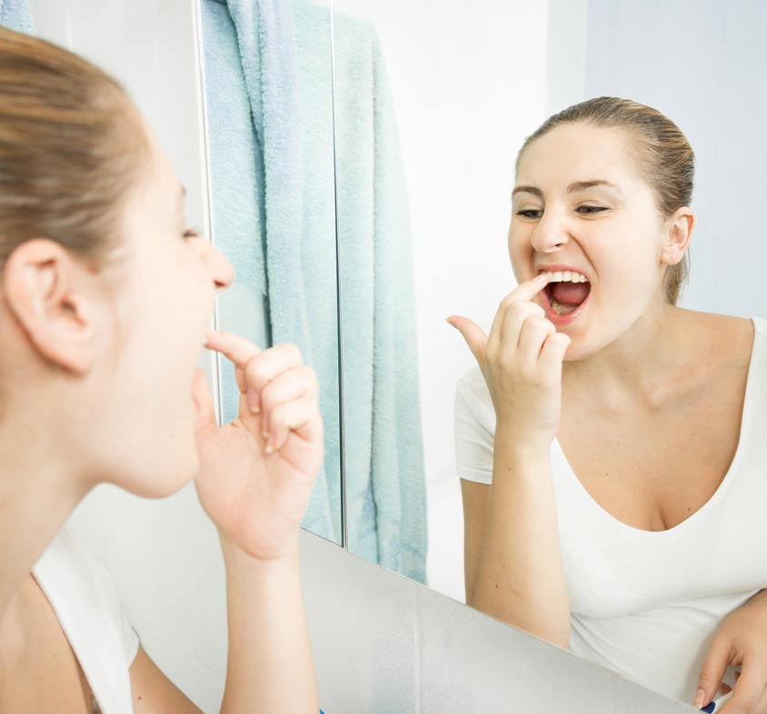 girl checking her teeth in the mirror